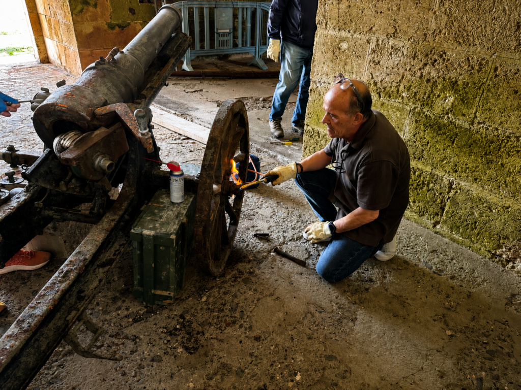 Restaurador trabajando sobre la rueda de un antiguo cañón en el interior del fuerte.
