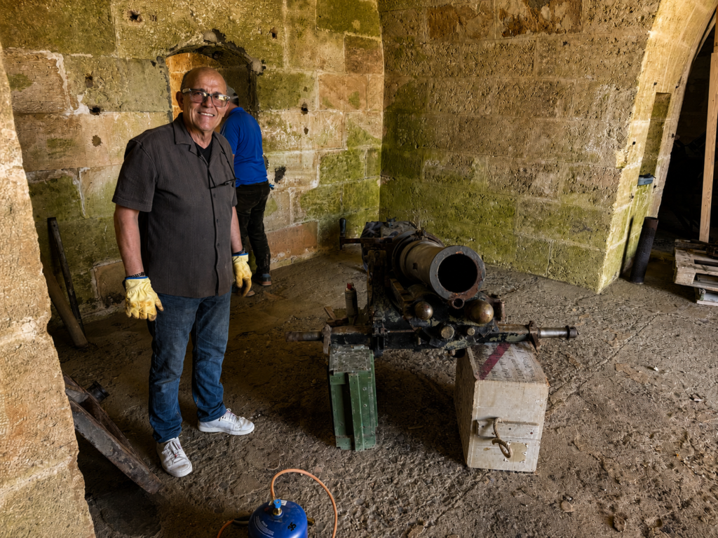 Retrato ambiental del restaurador junto al antiguo cañón dentro de la galería histórica.