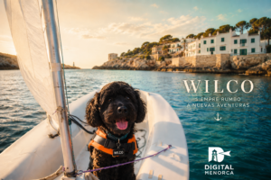 Wilco navegando en una pequeña embarcación de vela frente a la costa de Menorca durante el atardecer, con el mar en calma y el logo de Digital Menorca.